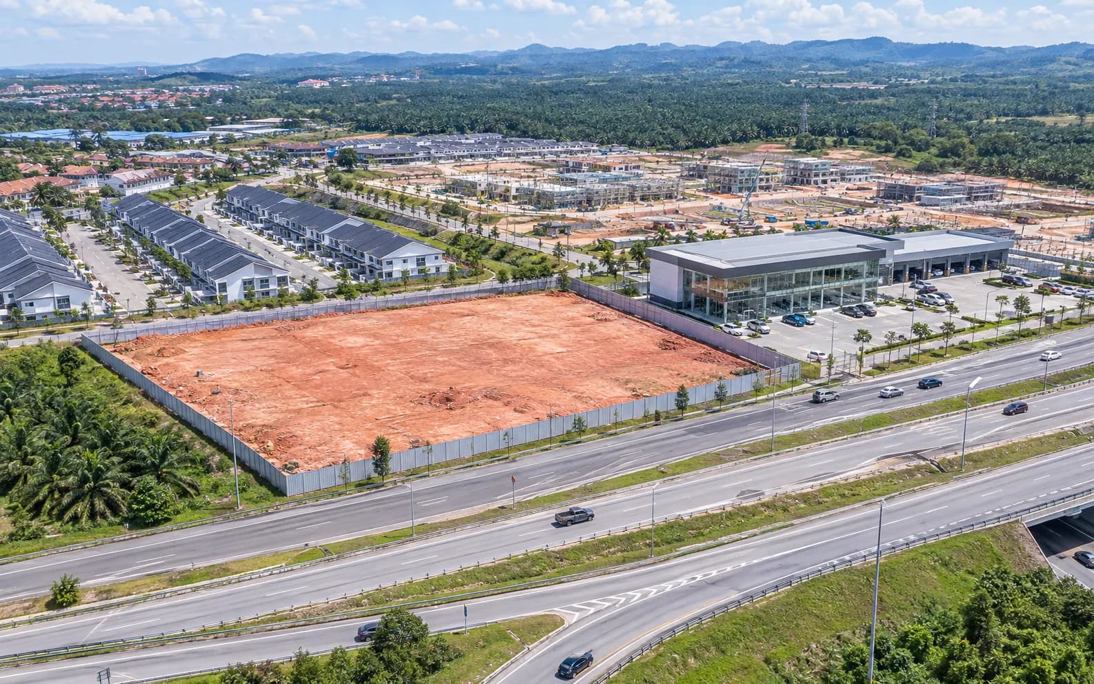 Illustration: cleared car showroom land by a highway interchange in a growing Malaysian township.